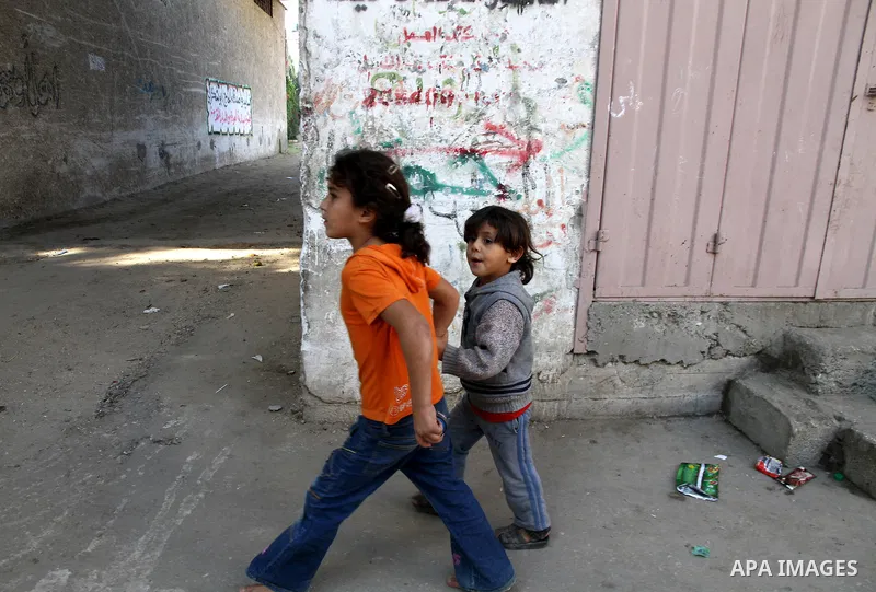 Palestinian girls get out of their houses after Israeli aircraft threatened to target the area, in the Jebaliya refugee camp, in Gaza Strip, Tuesday, Nov. 20, 2012. Palestinian families are fleeing their homes destroyed...