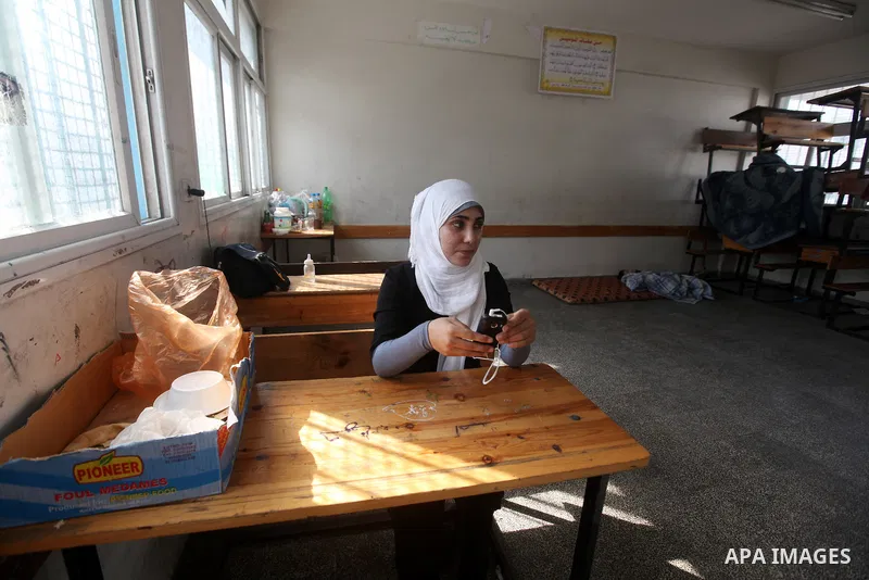 A Displaced Palestinian woman from al-Atatra area, who feld her house, checks her mobile phone, in her temporary residence, at a United Nations-run school in Gaza City, on November 20, 2012. Israeli leaders discussed an...