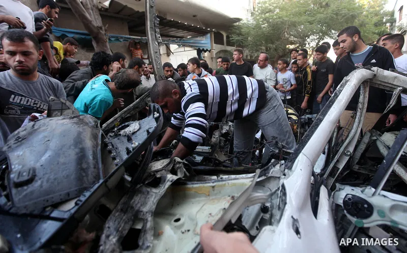 Palestinian gather arround a destroyed car following an Israeli strike in Gaza City on November 20, 2012. Israel's air force dropped leaflets across several districts of Gaza City urging people to evacuate their homes "i...