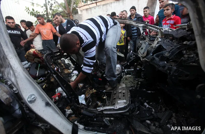Palestinian gather arround a destroyed car following an Israeli strike in Gaza City on November 20, 2012. Israel's air force dropped leaflets across several districts of Gaza City urging people to evacuate their homes "i...