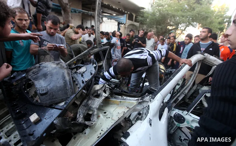 Palestinian gather arround a destroyed car following an Israeli strike in Gaza City on November 20, 2012. Israel's air force dropped leaflets across several districts of Gaza City urging people to evacuate their homes "i...