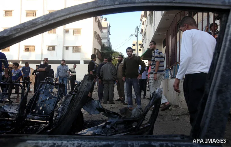 Palestinian gather arround a destroyed car following an Israeli strike in Gaza City on November 20, 2012. Israel's air force dropped leaflets across several districts of Gaza City urging people to evacuate their homes "i...