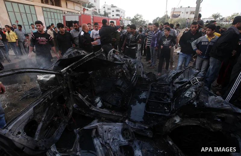 Palestinian gather arround a destroyed car following an Israeli strike in Gaza City on November 20, 2012. Israel's air force dropped leaflets across several districts of Gaza City urging people to evacuate their homes "i...