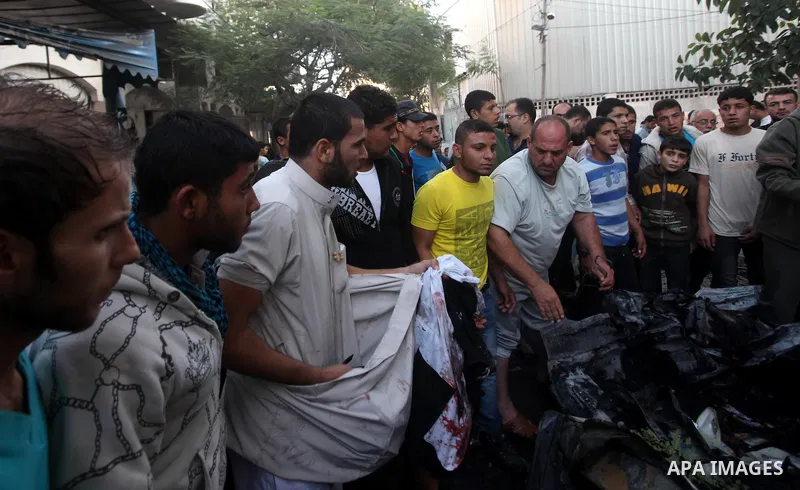 Palestinian gather arround a destroyed car following an Israeli strike in Gaza City on November 20, 2012. Israel's air force dropped leaflets across several districts of Gaza City urging people to evacuate their homes "i...