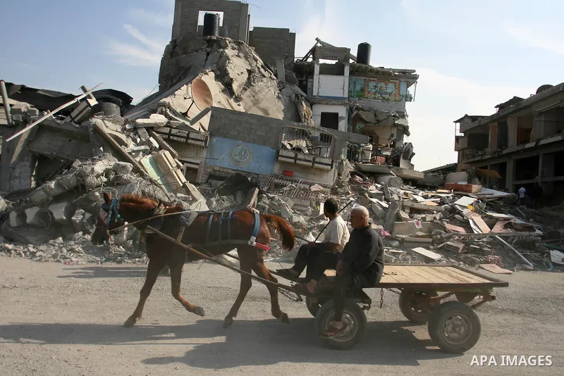 Palestinians ride a cart past a damaged buildings following Israeli air strikes in Gaza city on November 20, 2012. The Israeli military said it attacked about 100 targets in the coastal strip during the night, using airc...