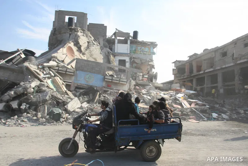 Palestinians ride a motorcycle past a damaged buildings following Israeli air strikes in Gaza city on November 20, 2012. The Israeli military said it attacked about 100 targets in the coastal strip during the night, usin...