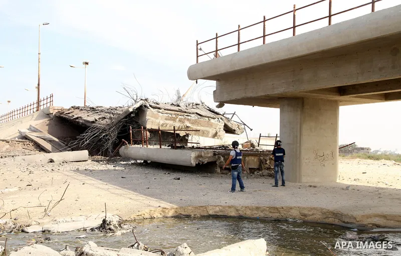 Palestinian photographers stand in front A bridge connecting the north and central part of the Gaza Strip, which was destroyed overnight by an Israeli airstrike in Gaza City, 21 November 2012. Palestinian militants renew...