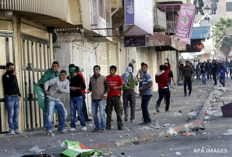 Palestinian youths throw stones during clashes with Israeli troops against Israel's operations in Gaza Strip in the West Bank city of Hebron, Tuesday, Nov. 20, 2012. Photo by Mamoun Wazwazi