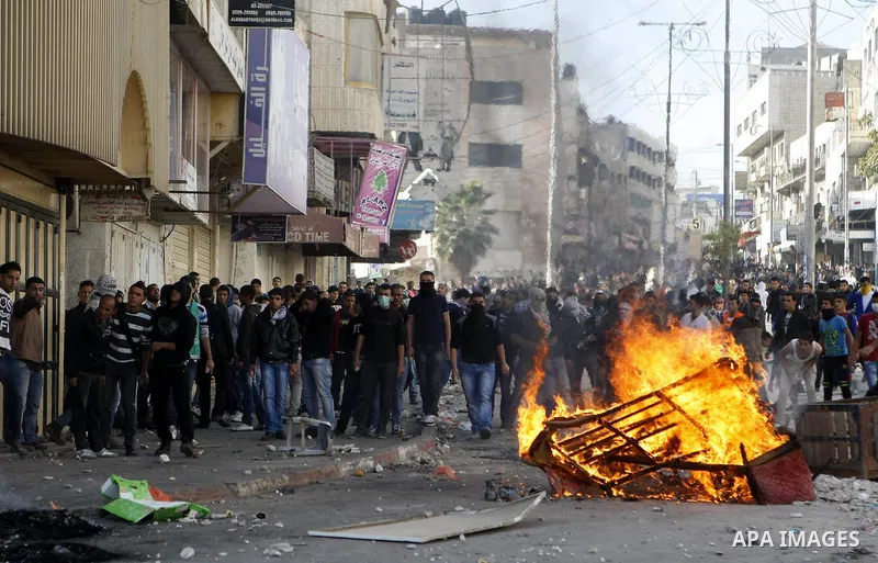 Palestinian youths throw stones during clashes with Israeli troops against Israel's operations in Gaza Strip in the West Bank city of Hebron, Tuesday, Nov. 20, 2012. Photo by Mamoun Wazwazi