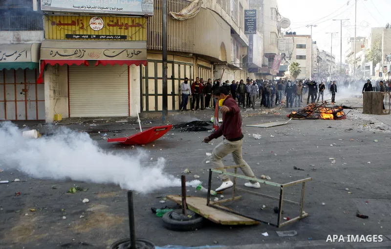 Palestinian youths throw stones during clashes with Israeli troops against Israel's operations in Gaza Strip in the West Bank city of Hebron, Tuesday, Nov. 20, 2012. Photo by Mamoun Wazwazi