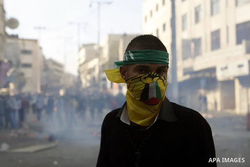 Palestinian youths throw stones during clashes with Israeli troops against Israel's operations in Gaza Strip in the West Bank city of Hebron, Tuesday, Nov. 20, 2012. Photo by Mamoun Wazwazi