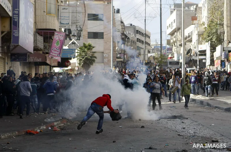 Palestinian youths throw stones during clashes with Israeli troops against Israel's operations in Gaza Strip in the West Bank city of Hebron, Tuesday, Nov. 20, 2012. Photo by Mamoun Wazwazi