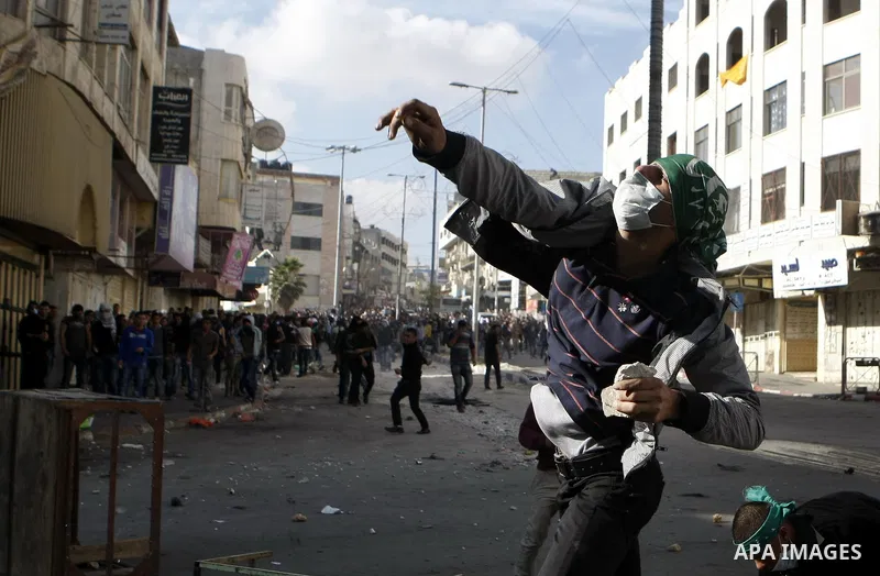 Palestinian youths throw stones during clashes with Israeli troops against Israel's operations in Gaza Strip in the West Bank city of Hebron, Tuesday, Nov. 20, 2012. Photo by Mamoun Wazwazi