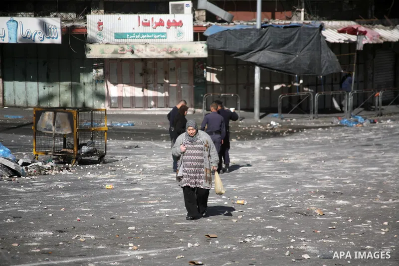Palestinians walk in a street as shops closed against a lockout against the Israeli military action on Gaza strip, in the West Bank city of Hebron, November 21, 2012. Israeli air strikes shook the Gaza Strip and Palestin...