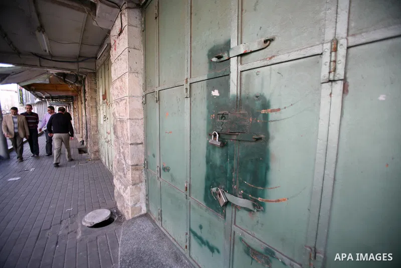 Palestinians walk in a street as shops closed against a lockout against the Israeli military action on Gaza strip, in the West Bank city of Hebron, November 21, 2012. Israeli air strikes shook the Gaza Strip and Palestin...