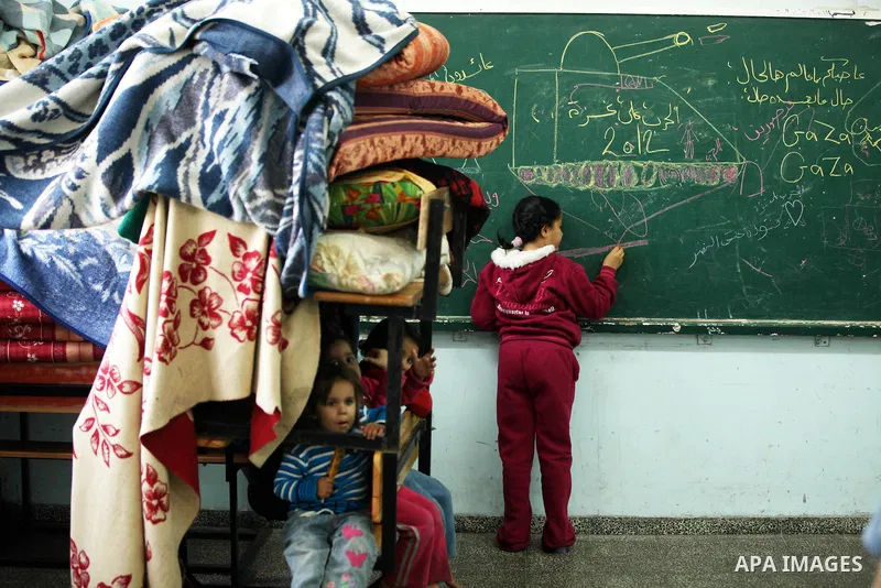 Palestinians gather where displaced families are staying after evacuating their homes earlier this week to take shelter at a United Nations (UN) school in Gaza City on November 21, 2012. Palestinian president Mahmud Abba...