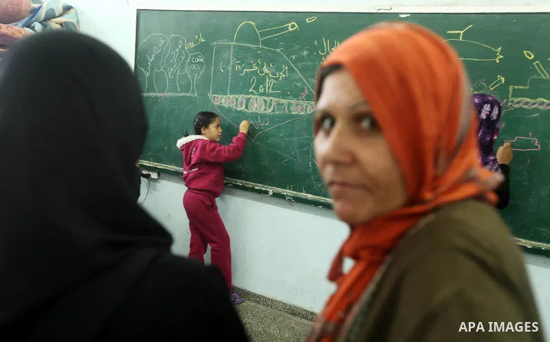 Palestinians gather where displaced families are staying after evacuating their homes earlier this week to take shelter at a United Nations (UN) school in Gaza City on November 21, 2012. Palestinian president Mahmud Abba...