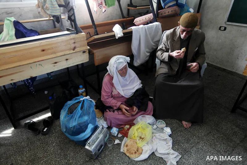 Palestinians gather where displaced families are staying after evacuating their homes earlier this week to take shelter at a United Nations (UN) school in Gaza City on November 21, 2012. Palestinian president Mahmud Abba...