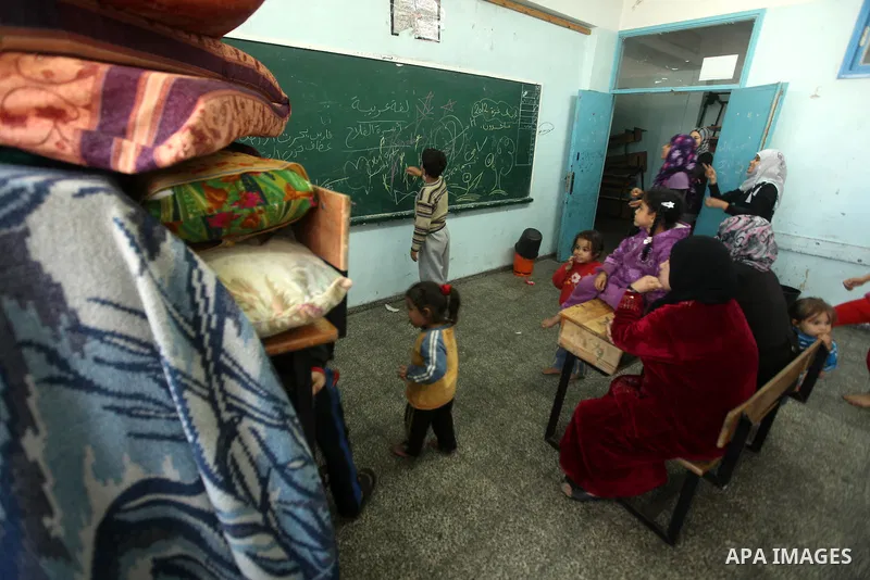 Palestinians gather where displaced families are staying after evacuating their homes earlier this week to take shelter at a United Nations (UN) school in Gaza City on November 21, 2012. Palestinian president Mahmud Abba...