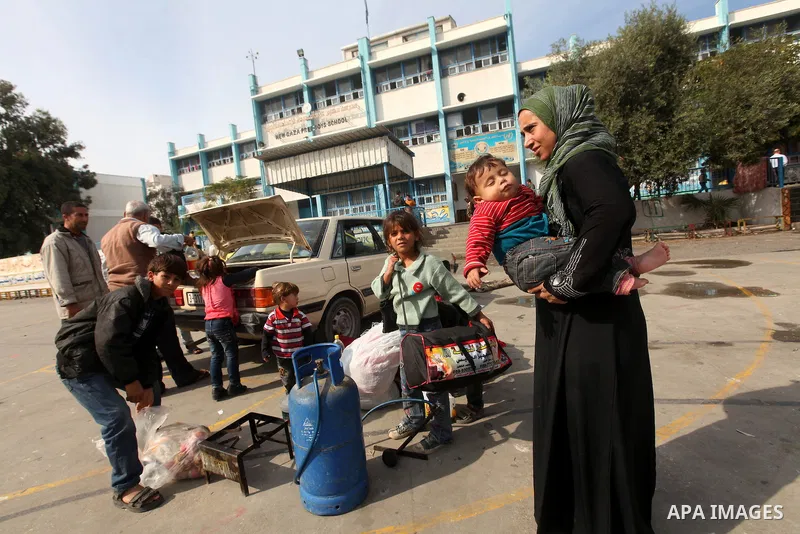 Palestinians gather where displaced families are staying after evacuating their homes earlier this week to take shelter at a United Nations (UN) school in Gaza City on November 21, 2012. Palestinian president Mahmud Abba...