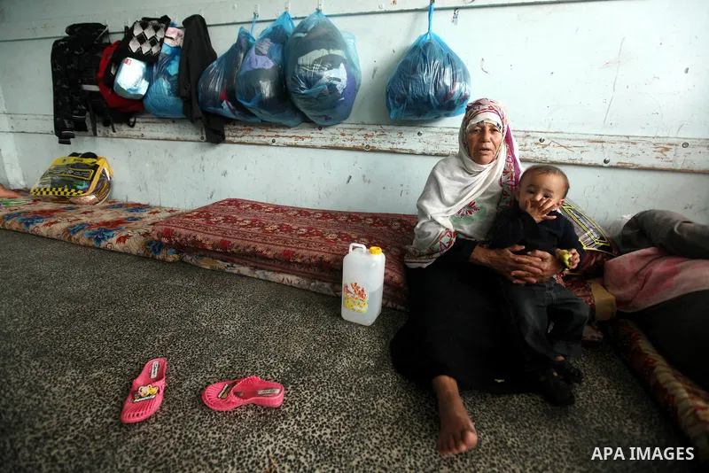 Palestinians gather where displaced families are staying after evacuating their homes earlier this week to take shelter at a United Nations (UN) school in Gaza City on November 21, 2012. Palestinian president Mahmud Abba...