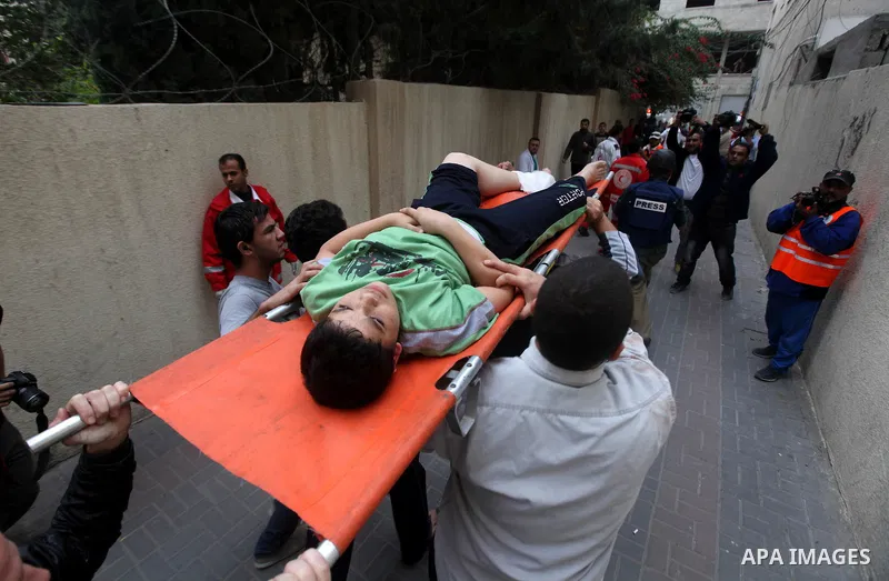 Palestinians carry a wounded youth after an Israeli strike in Gaza City on November 21, 2012. Naim was killed in a second Israeli strike on the building housing AFP'S Gaza offices, Hamas health officials said. No AFP jou...