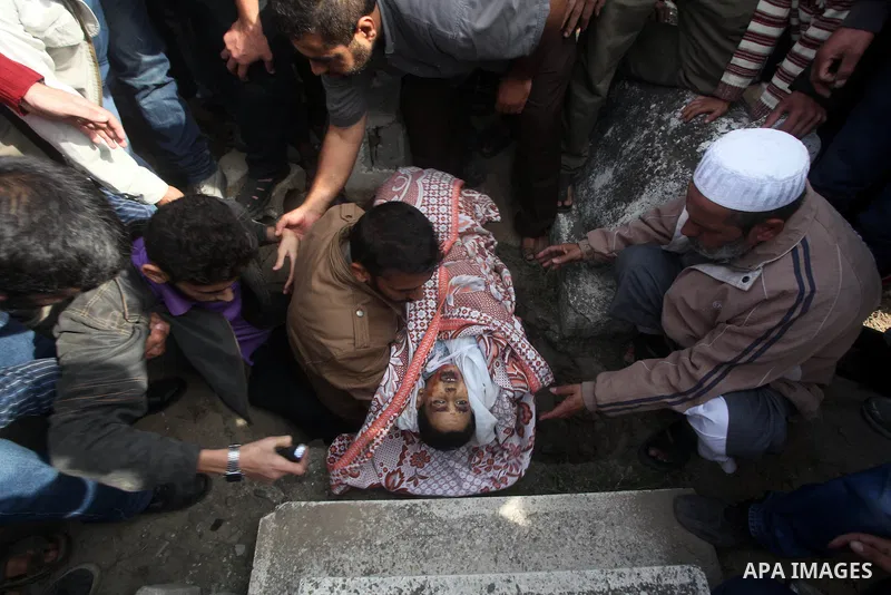 A Palestinian man carries the body of Mohammed Ashour, 10, killed the previous day in an Israeli air strike on Gaza City, during his funeral, Wednesday, Nov. 21, 2012. Israeli aircraft pounded Gaza with at least 30 strik...