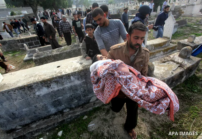 A Palestinian man carries the body of Mohammed Ashour, 10, killed the previous day in an Israeli air strike on Gaza City, during his funeral, Wednesday, Nov. 21, 2012. Israeli aircraft pounded Gaza with at least 30 strik...