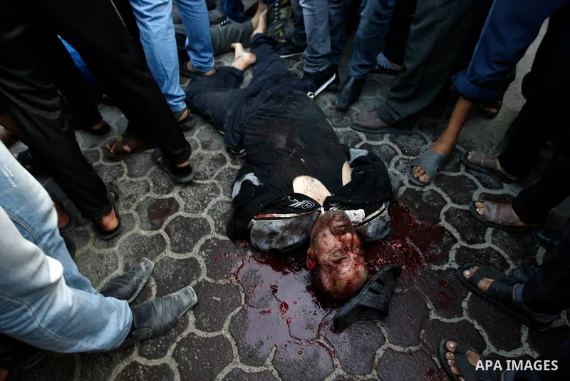 Palestinians gather around The body of an alleged collaborator in Gaza City November 20, 2012. Gunmen executed six "collaborators" in Gaza City , witnesses said on November 20, adding that notices were pinned to their bo...