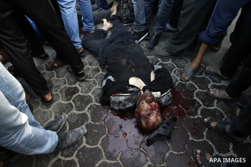 Palestinians gather around The body of an alleged collaborator in Gaza City November 20, 2012. Gunmen executed six "collaborators" in Gaza City , witnesses said on November 20, adding that notices were pinned to their bo...