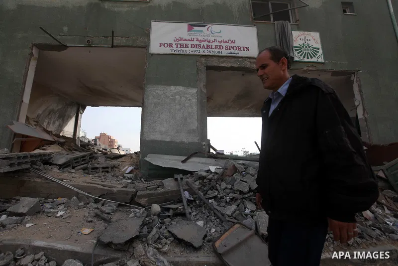 A Palestinian man walks in front of a destroyed gridiron after an israeli air strike in Gaza City, 21 November 2012. Palestinian militants renewed their rocket fire on Israel 21 November and Israel continued pounding tar...