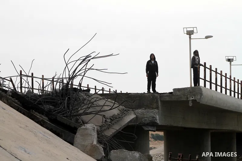 Palestinians look at Wadi Gaza bridge, a strategic link between the northern and southern areas of the Gaza Strip, following an overnight Israeli air strike on November 21, 2012. Today's bloodshed raised to 148 the total...
