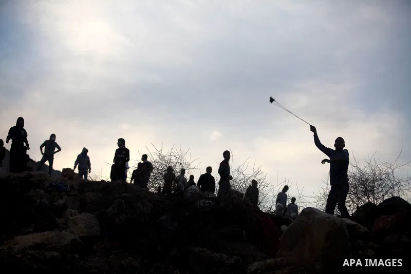 Palestinians youth throw a stone towards Israeli forces at the Qalandia checkpoint, in the Israeli occupied West Bank, on November 21, 2012. Israel launched its offensive on November 14 with the targeted killing of a Ham...