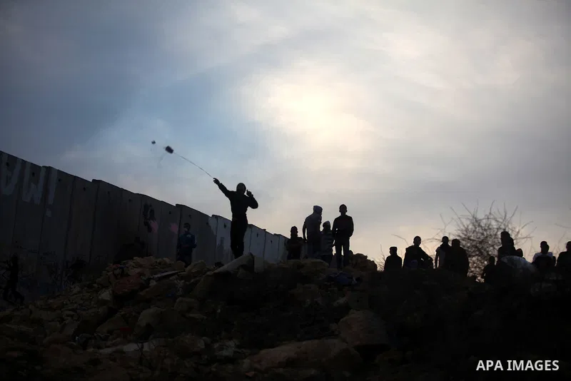 Palestinians youth throw a stone towards Israeli forces at the Qalandia checkpoint, in the Israeli occupied West Bank, on November 21, 2012. Israel launched its offensive on November 14 with the targeted killing of a Ham...