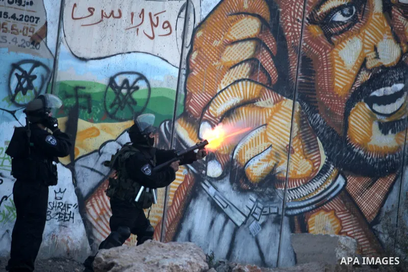 Israeli soldiers fire tear gas towards stone throwers demonstrating against the Israeli military offensive on the Gaza Strip at the Qalandia checkpoint, in the Israeli occupied West Bank, on November 21, 2012 .Israel lau...