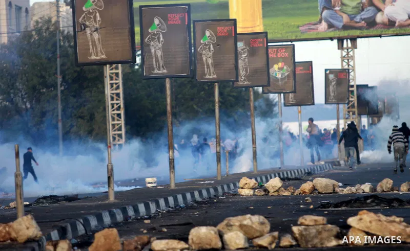 Palestinian protesters run cover from tear gas during clashes in the West Bank city of Nablus, on November 21, 2012. The West Bank has witnessed almost daily demonstrations in support of Gaza Palestinians who have faced...