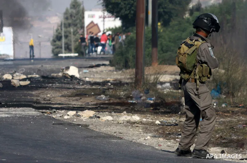 An Israeli soldier stands fires tear gas at Palestinian protesters during clashes in the West Bank city of Nablus, on November 21, 2012. The West Bank has witnessed almost daily demonstrations in support of Gaza Palestin...