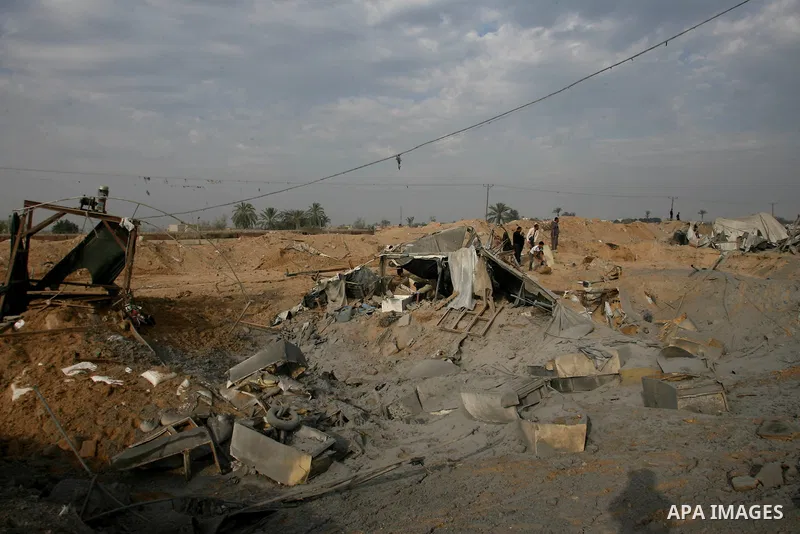 Palestinians walk past a crater near bombed smuggling tunnels between the southern Gaza Strip and Egypt in the border town of Rafah on November 22, 2012. A ceasefire took hold in and around Gaza after a week of cross-bor...