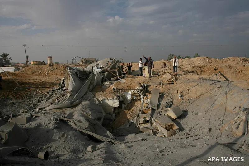 Palestinians walk past a crater near bombed smuggling tunnels between the southern Gaza Strip and Egypt in the border town of Rafah on November 22, 2012. A ceasefire took hold in and around Gaza after a week of cross-bor...