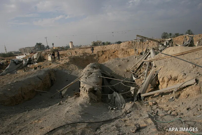 Palestinians walk past a crater near bombed smuggling tunnels between the southern Gaza Strip and Egypt in the border town of Rafah on November 22, 2012. A ceasefire took hold in and around Gaza after a week of cross-bor...