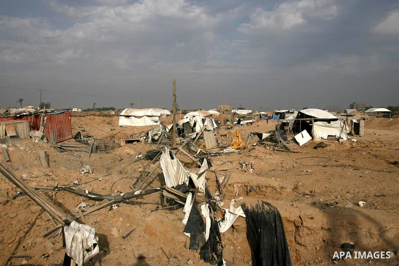 Palestinians walk past a crater near bombed smuggling tunnels between the southern Gaza Strip and Egypt in the border town of Rafah on November 22, 2012. A ceasefire took hold in and around Gaza after a week of cross-bor...