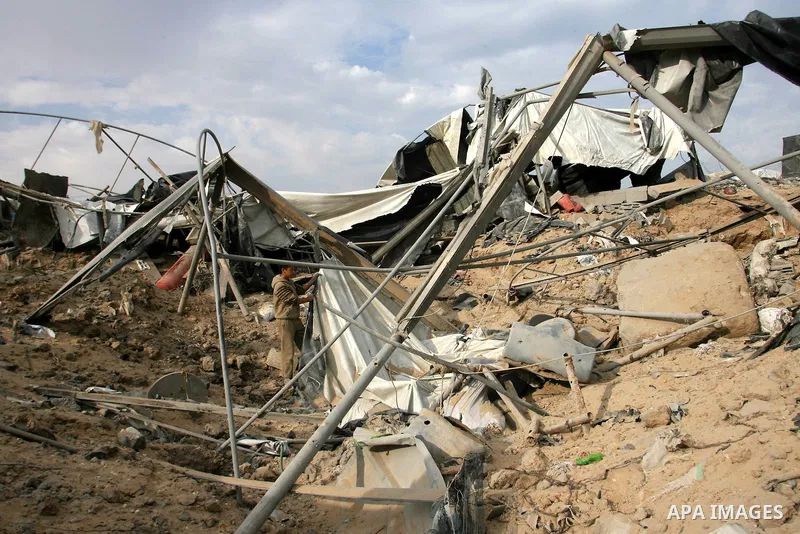 Palestinians walk past a crater near bombed smuggling tunnels between the southern Gaza Strip and Egypt in the border town of Rafah on November 22, 2012. A ceasefire took hold in and around Gaza after a week of cross-bor...