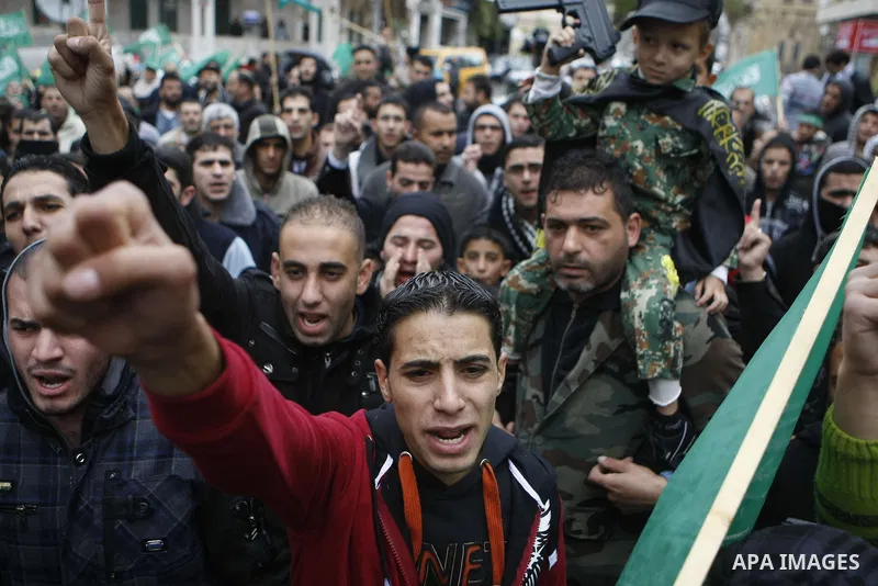 Palestinian supporters of the Islamist movement Hamas gesture and wave the movement's flag during a demonstration in the West Bank city of Hebron on November 23, 2012. Photo by Mamoun Wazwaz