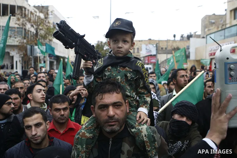 Palestinian supporters of the Islamist movement Hamas gesture and wave the movement's flag during a demonstration in the West Bank city of Hebron on November 23, 2012. Photo by Mamoun Wazwaz