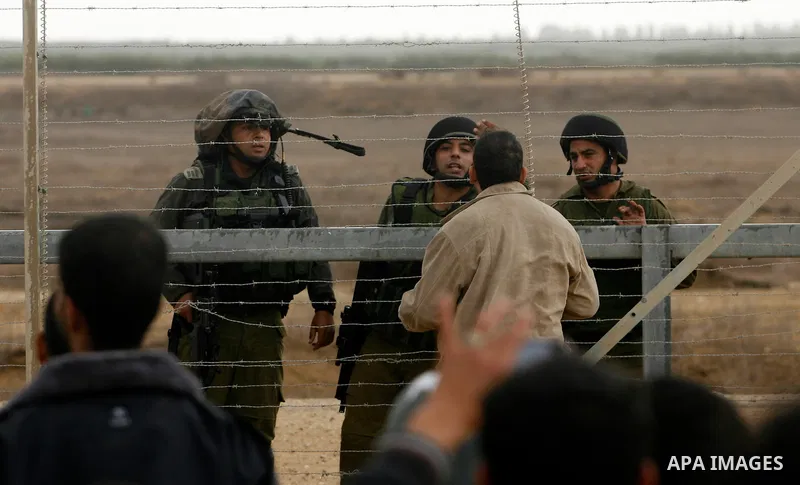 A Palestinian man speaks with Israeli soldiers on the border between Gaza strip and Israel in the east of Khan Younis southern Gaza strip November 23, 2012. Israeli troops at the Gaza border shot dead a Palestinian man a...