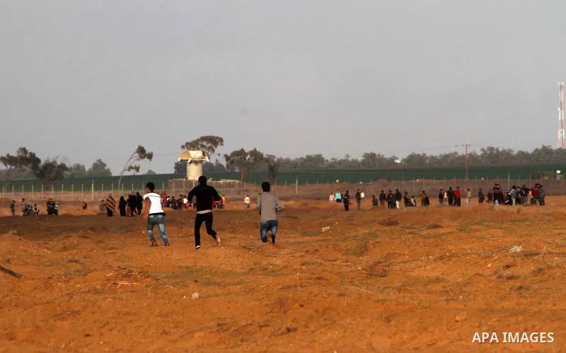Palestinians stand near the Israeli Gaza border fence in east of Khan Younis, southern Gaza Strip, Friday, Nov. 23, 2012. Hundreds of Gaza crowds surged toward Israel's border fence with the Hamas-ruled territory, in a n...