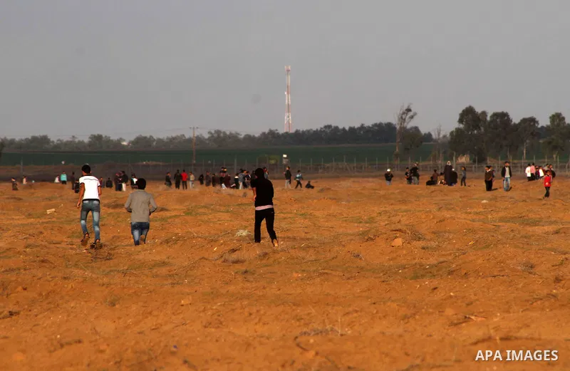 Palestinians stand near the Israeli Gaza border fence in east of Khan Younis, southern Gaza Strip, Friday, Nov. 23, 2012. Hundreds of Gaza crowds surged toward Israel's border fence with the Hamas-ruled territory, in a n...