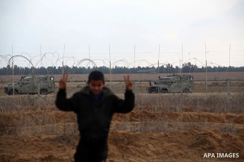 Palestinians stand near the Israeli Gaza border fence in east of Khan Younis, southern Gaza Strip, Friday, Nov. 23, 2012. Hundreds of Gaza crowds surged toward Israel's border fence with the Hamas-ruled territory, in a n...