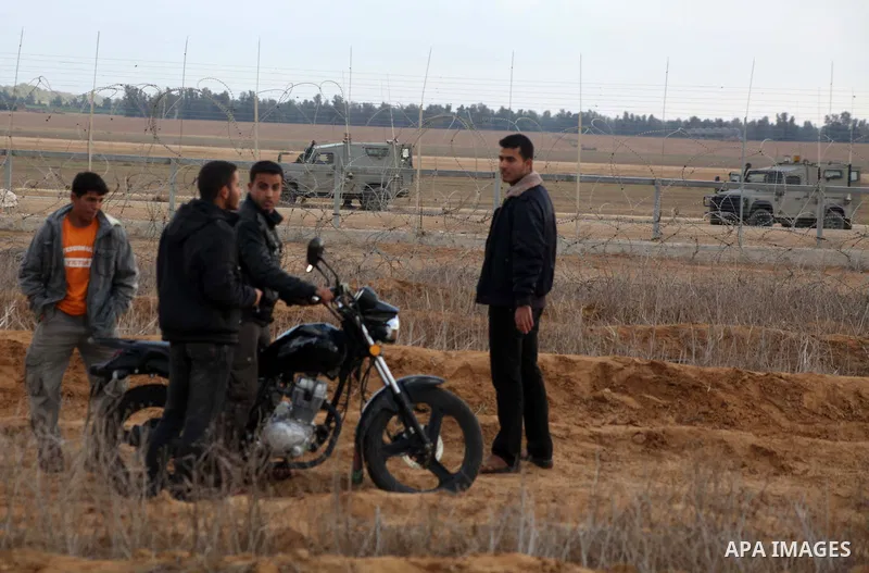 Palestinians stand near the Israeli Gaza border fence in east of Khan Younis, southern Gaza Strip, Friday, Nov. 23, 2012. Hundreds of Gaza crowds surged toward Israel's border fence with the Hamas-ruled territory, in a n...