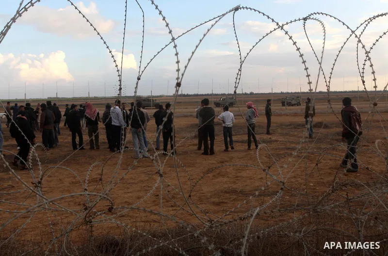 Palestinians stand near the Israeli Gaza border fence in east of Khan Younis, southern Gaza Strip, Friday, Nov. 23, 2012. Hundreds of Gaza crowds surged toward Israel's border fence with the Hamas-ruled territory, in a n...